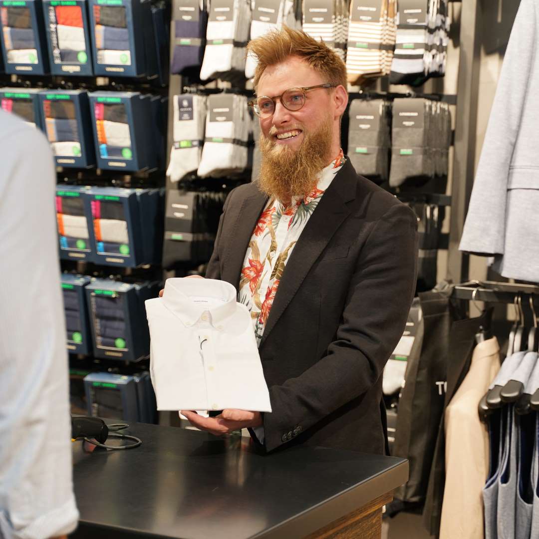 Medarbejder fra Tøjeksperten i Randers viser kunde hvid skjorte.